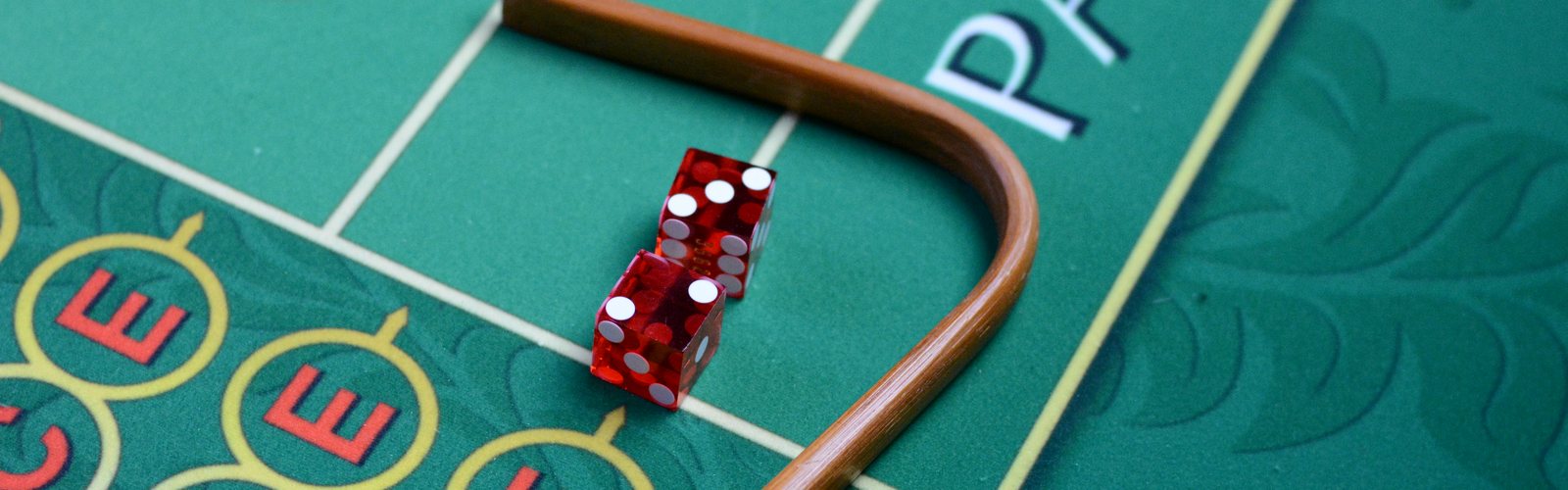Krupieen lapio ja punaiset nopat craps-pöydän vihreällä veralla
